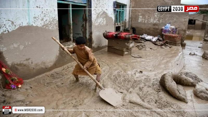 طفل يرفع الوحل من أمام منزله عقب فيضانات في أفغانستان